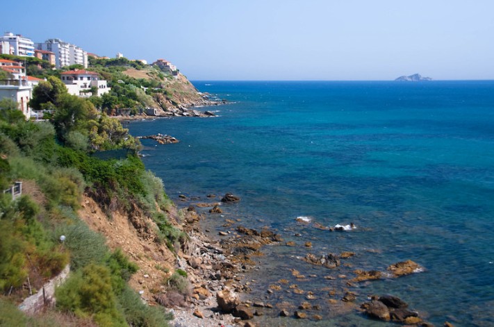 Vista panoramica della costa di Piombino con case lungo la scogliera e acqua cristallina.