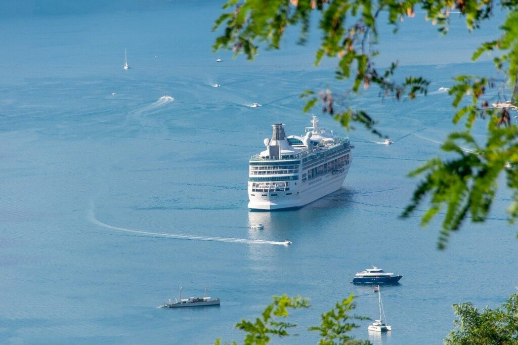 Nave da crociera nel mare di Piombino, circondata da piccole imbarcazioni e con acqua blu.