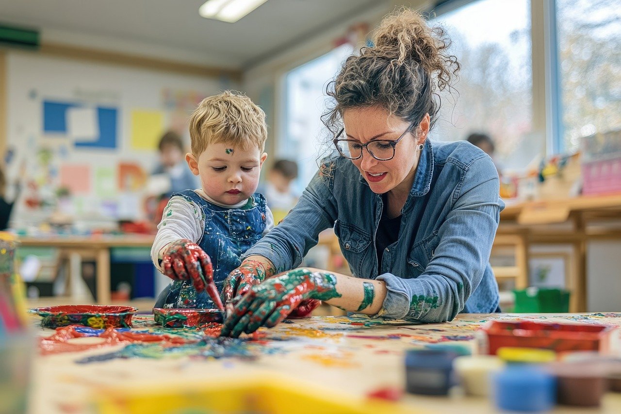 Bambino e adulto impegnati in un'attività artistica con pittura, entrambi con le mani coperte di colore.