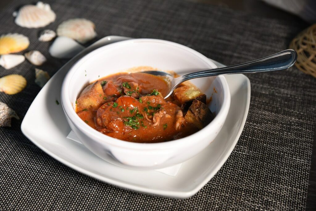 Zuppa di pesce servita in una ciotola bianca, decorata con prezzemolo e accompagnata da crostini.