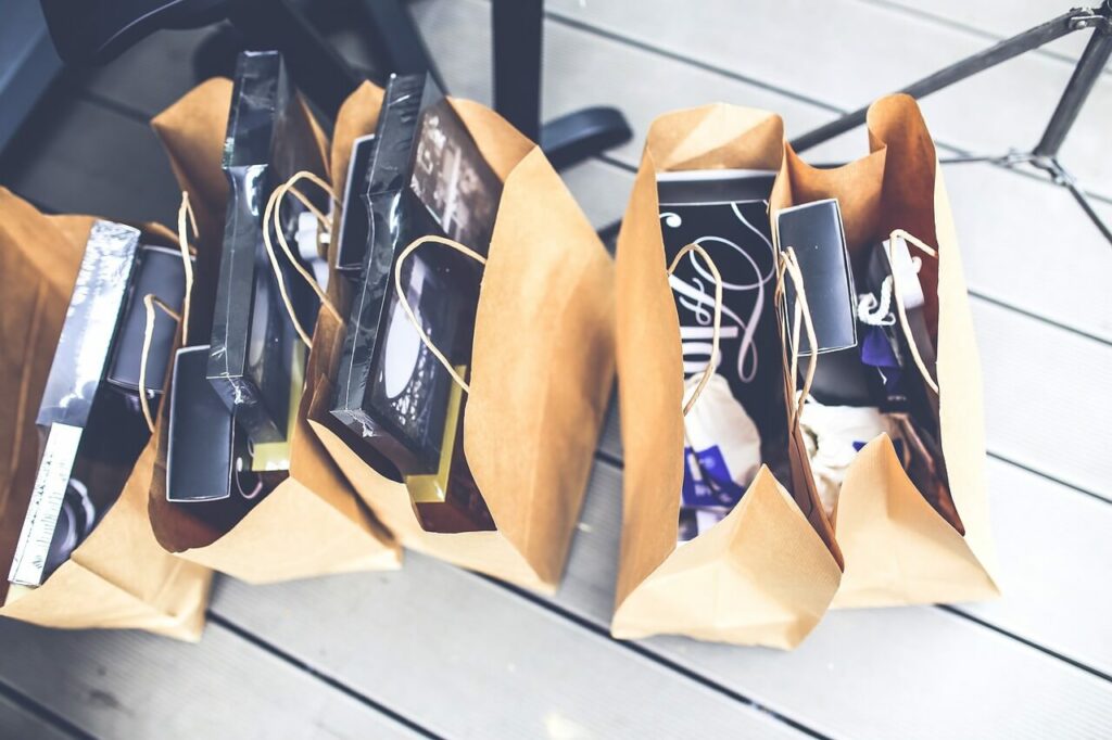 Sacchetti di carta marroni contenenti scatole regalo e altri articoli.