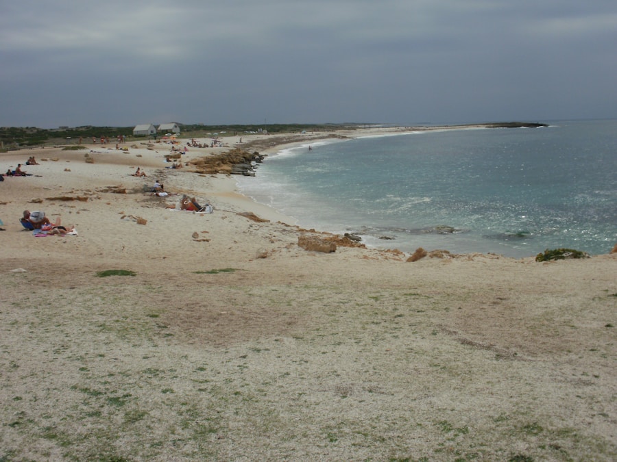 Spiaggia naturale con sabbia chiara, rocce sparse e mare cristallino, pochi bagnanti distesi sotto cielo nuvoloso a Calamoresca