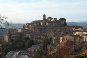 Veduta panoramica del borgo medievale di Suvereto, in Toscana, circondato da colline verdi e boschi.