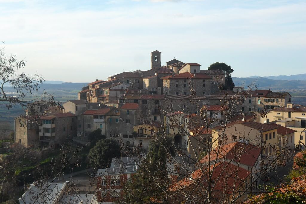 Veduta panoramica del borgo medievale di Suvereto, in Toscana, circondato da colline verdi e boschi.
