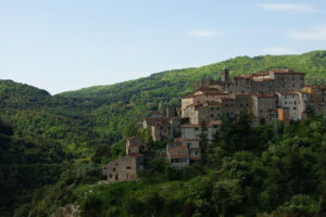 Veduta panoramica del borgo medievale di Suvereto, in Toscana, circondato da colline verdi e boschi.